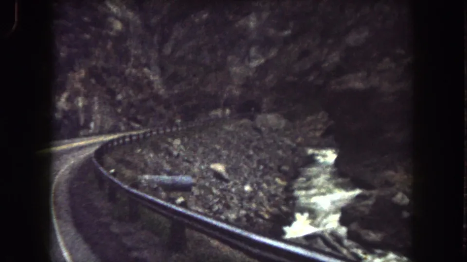Vintage 8mm view from Summit County, Colorado showing a bend in the mountain road and stream through a dark canyon.