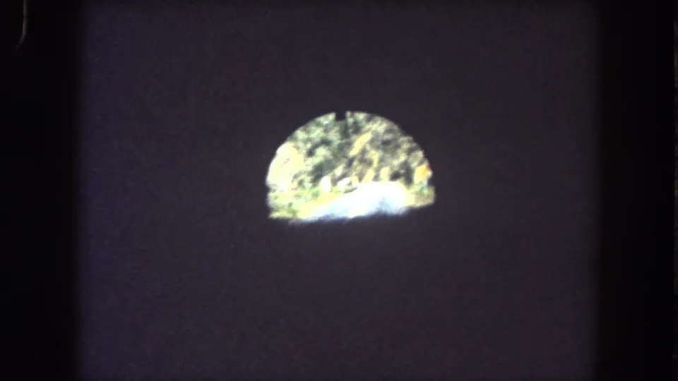 1962 8mm vehicle POV inside a dark Summit County tunnel, with a bright arched exit and faint mountain road visible beyond.