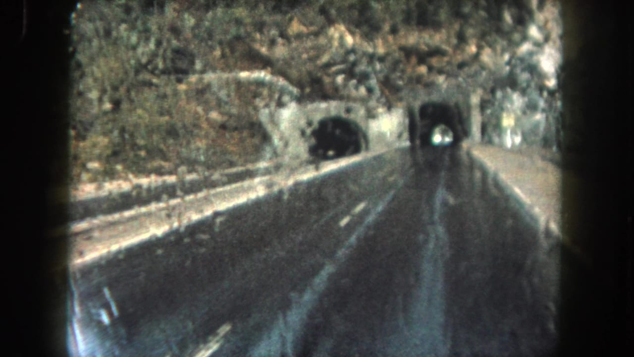 Vehicle POV on wet highway nearing a dark tunnel portal.