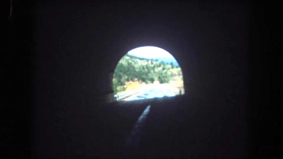Inside a dark highway tunnel, the 8mm camera looks toward a bright opening and road beyond in Summit County, Colorado.