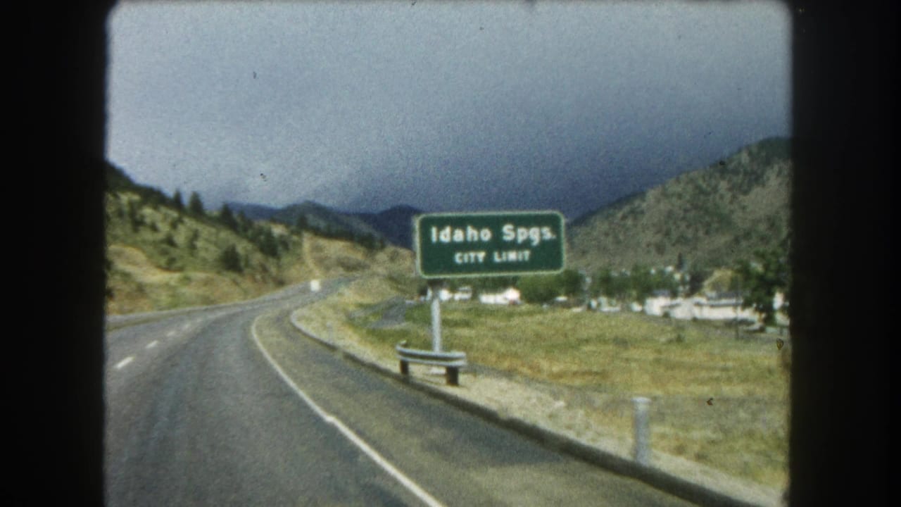 Readable Idaho Springs city-limit sign near the roadside as the vehicle follows a Colorado mountain highway.