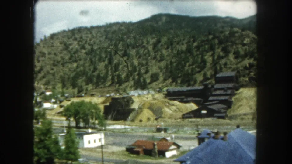 Summit County, Colorado town view with small buildings and roads below a wooded hillside and dark industrial-looking structure.