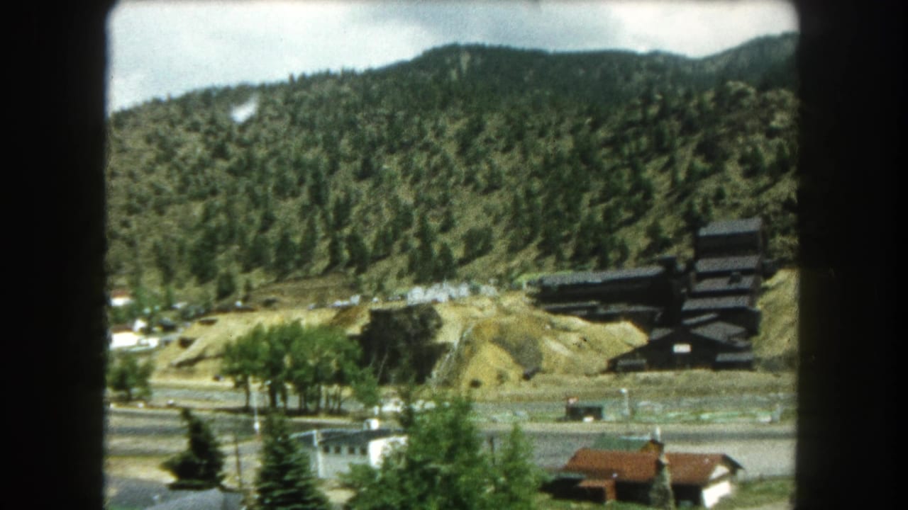 Summit County, Colorado travel footage frame with small buildings below a wooded hill and a dark structure set into the slope.