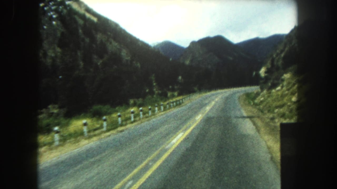 1962 8mm view of a two-lane road curving through forested mountains in Summit County, Colorado.