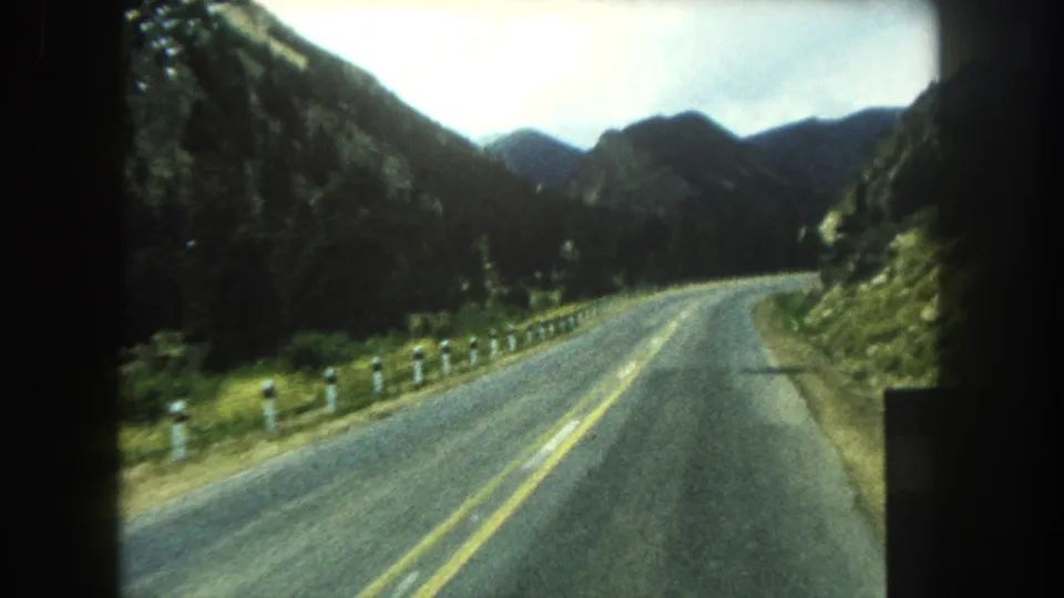 1962 8mm view of a two-lane road curving through forested mountains in Summit County, Colorado.