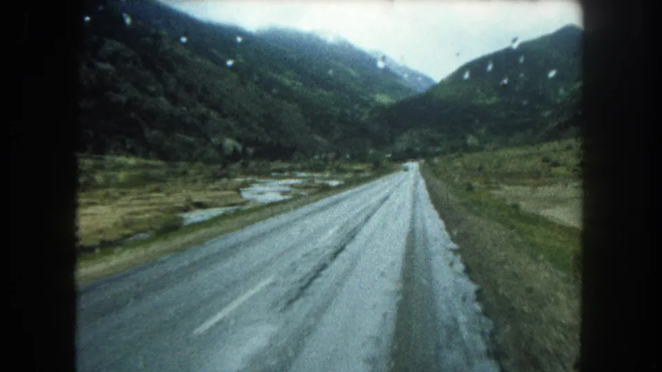 The final frame shows the rainy road stretching into a green Colorado valley, with soft 8mm color and visible frame borders.