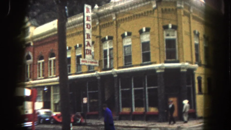 1962 Summit County street view with brick buildings, REDRAM sign, pedestrians, parked cars, and a red firetruck entering the frame edge.