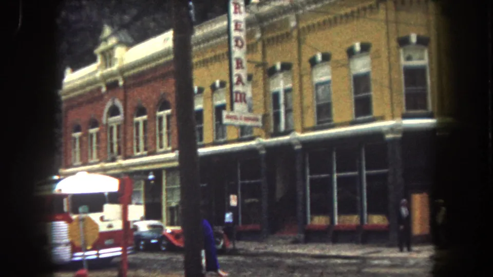 1962 Summit County street corner showing a red firetruck by brick storefronts, a vertical REDRAM sign, parked cars, and a pedestrian in dark clothing.