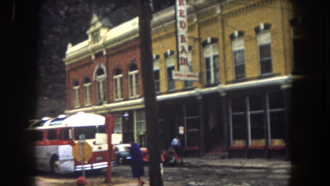 Red-and-white bus parked outside a two-story building with a vertical REDRAM sign.