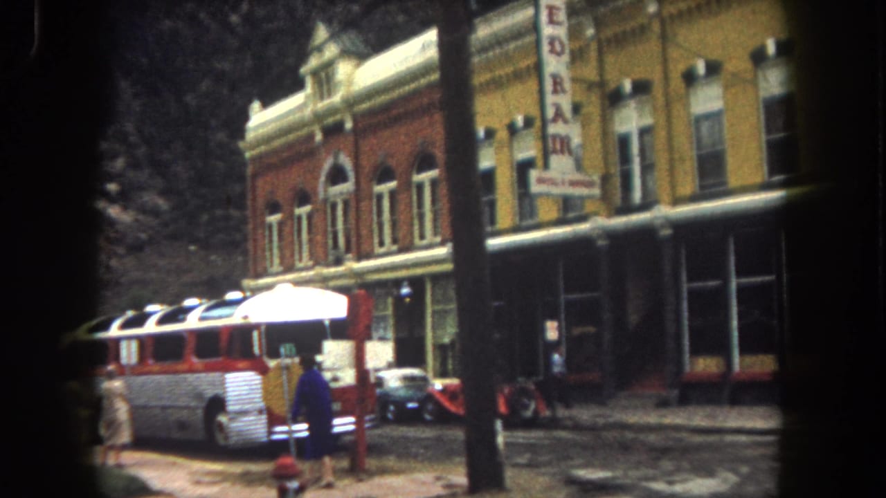 Bus, pedestrians, vintage car, and REDRAM sign in front of a historic-looking building.