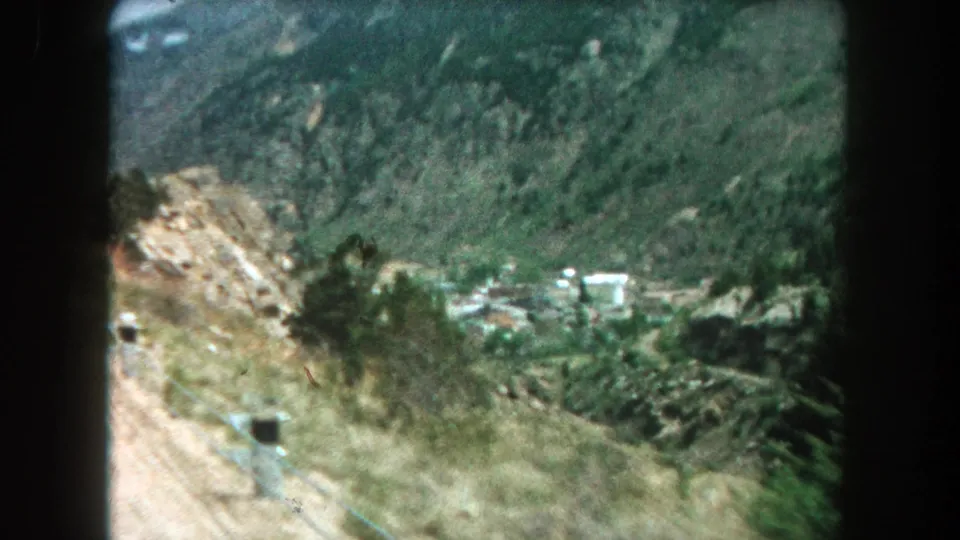 1962 Summit County scenic view looking down a mountain road toward trees, hillsides, and a small settlement in the valley.