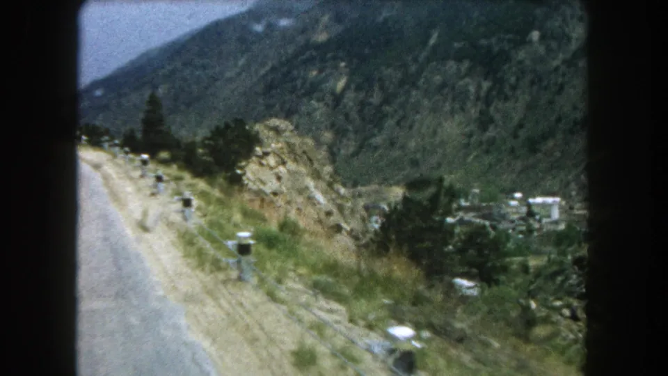 Summit County, Colorado road scene filmed on 8mm in 1962, showing a curving mountain road, white posts, and valley structures below.