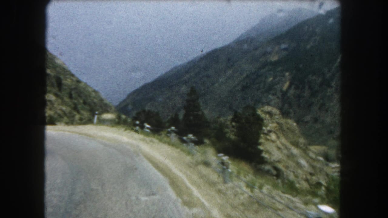 1962 Summit County, Colorado travel footage showing a road curving through a green mountain valley.