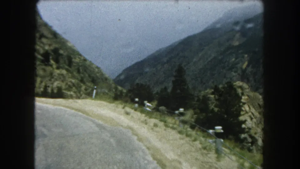 Moving 8mm view along a Summit County mountain road with green slopes and scattered pines.