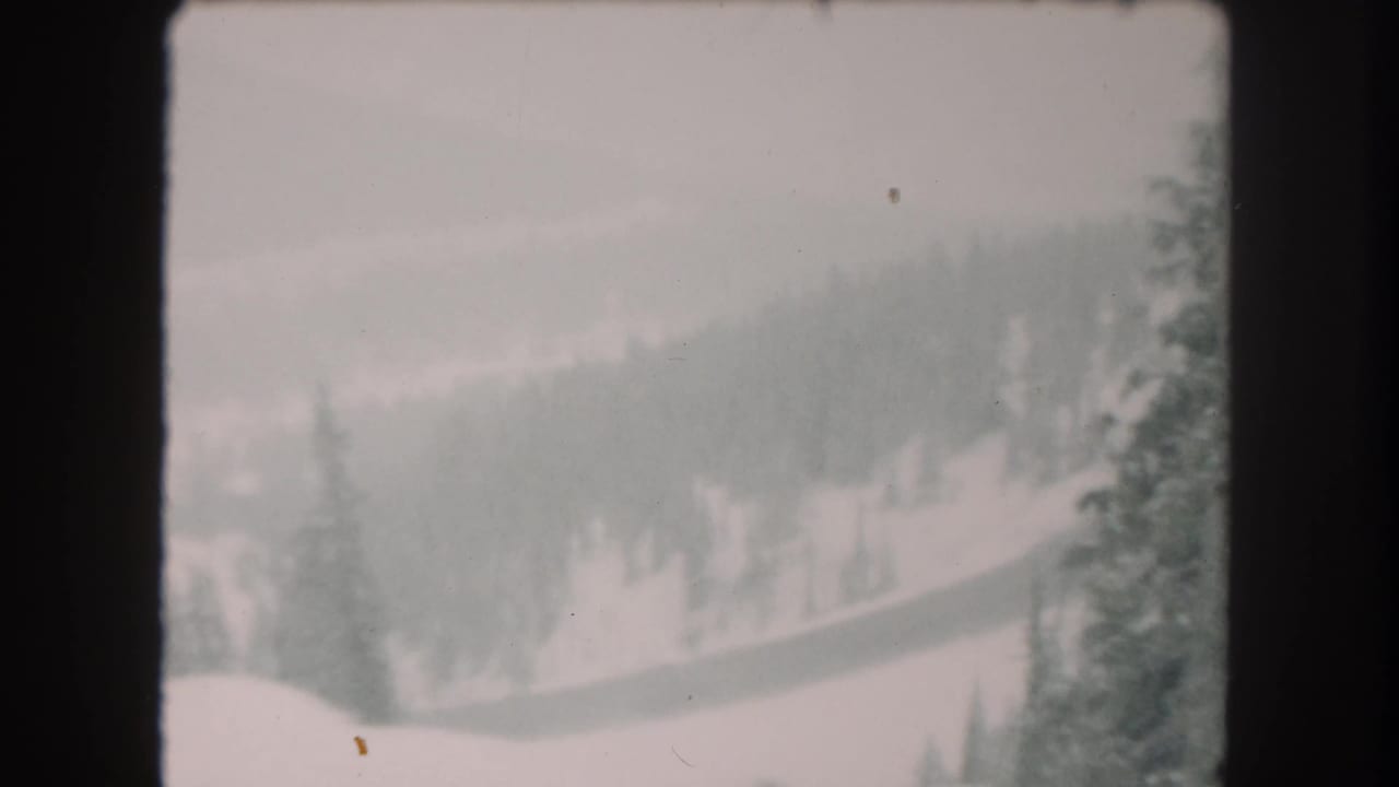 Soft 8mm view of a snowy Summit County hillside with scattered evergreens and a pale overcast sky, based on the 1962 metadata.