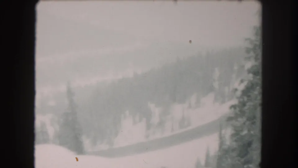 Soft 8mm view of a snowy Summit County hillside with scattered evergreens and a pale overcast sky, based on the 1962 metadata.