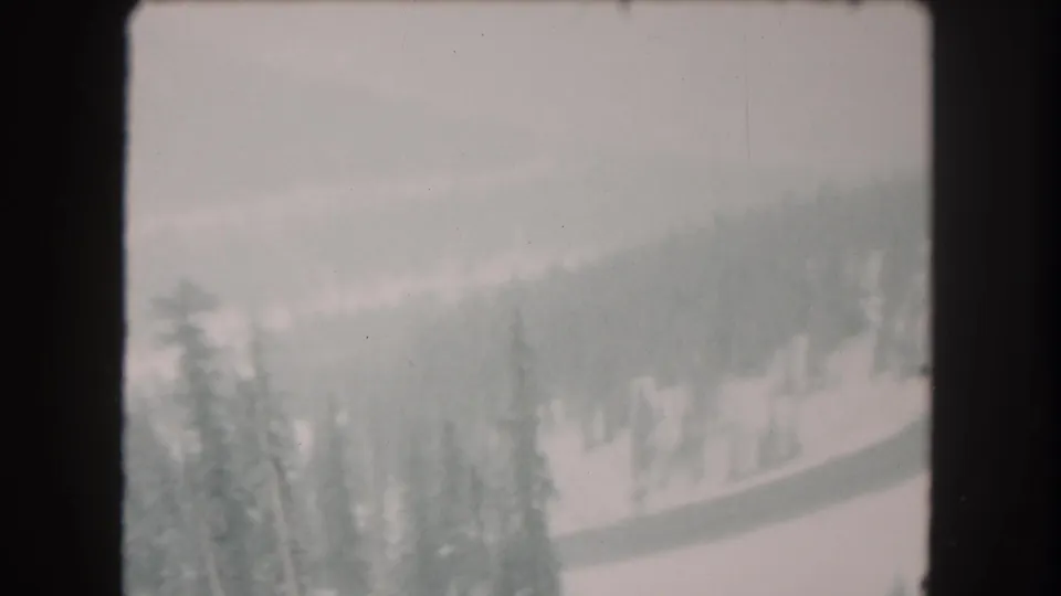 Summit County winter landscape frame showing snow-covered wooded hills, scattered evergreens, and visible 8mm film borders.