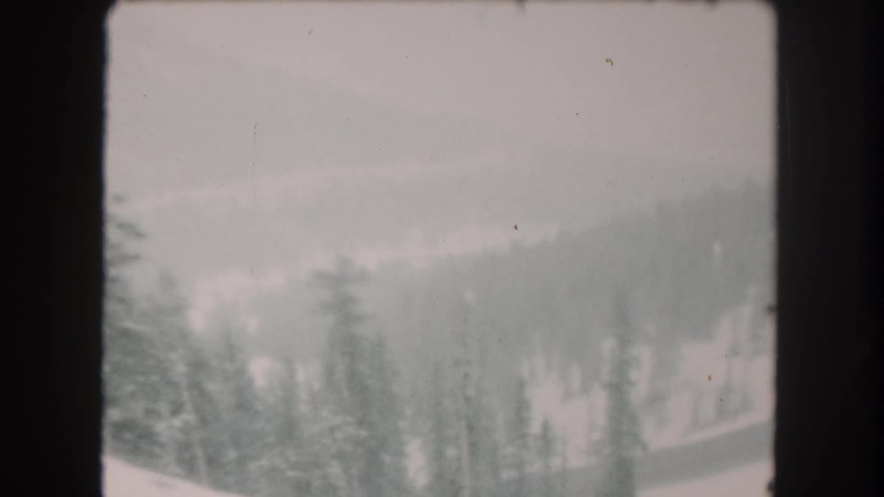 1962 Summit County, Colorado frame with snowy evergreens and distant terrain softened by overcast low visibility.