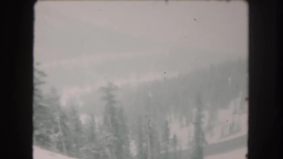 1962 Summit County, Colorado frame with snowy evergreens and distant terrain softened by overcast low visibility.