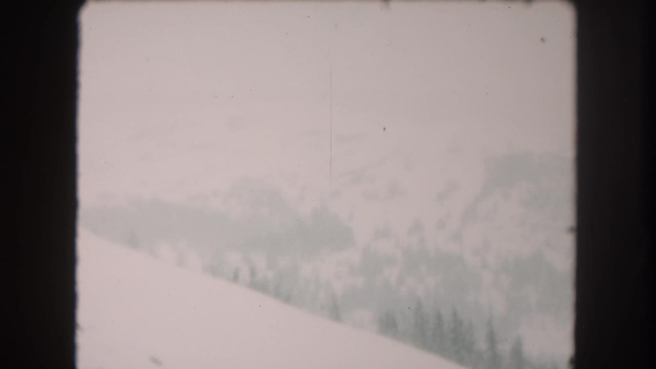 Snowy Summit County landscape on 8mm film, showing a sloped foreground, muted distant trees, and soft winter haze.