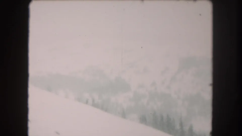 Snowy Summit County landscape on 8mm film, showing a sloped foreground, muted distant trees, and soft winter haze.