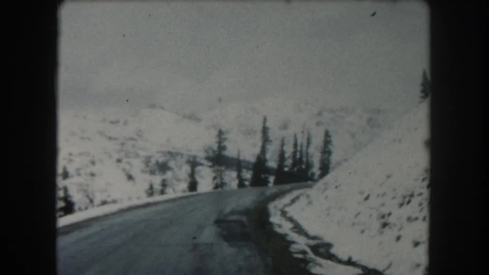 Summit County, Colorado road-trip footage from 1962 appears to show a paved mountain road bordered by snow and dark conifers.
