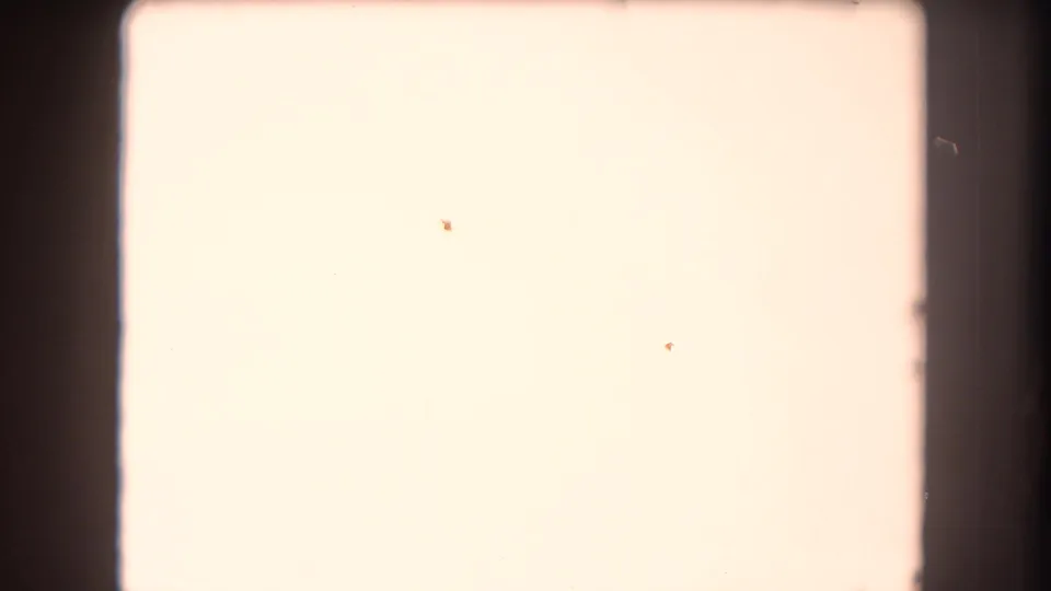 Overexposed 8mm frame from the 1962 Summit County clip, showing pale film area, dark gate edges, and small dust or processing marks.