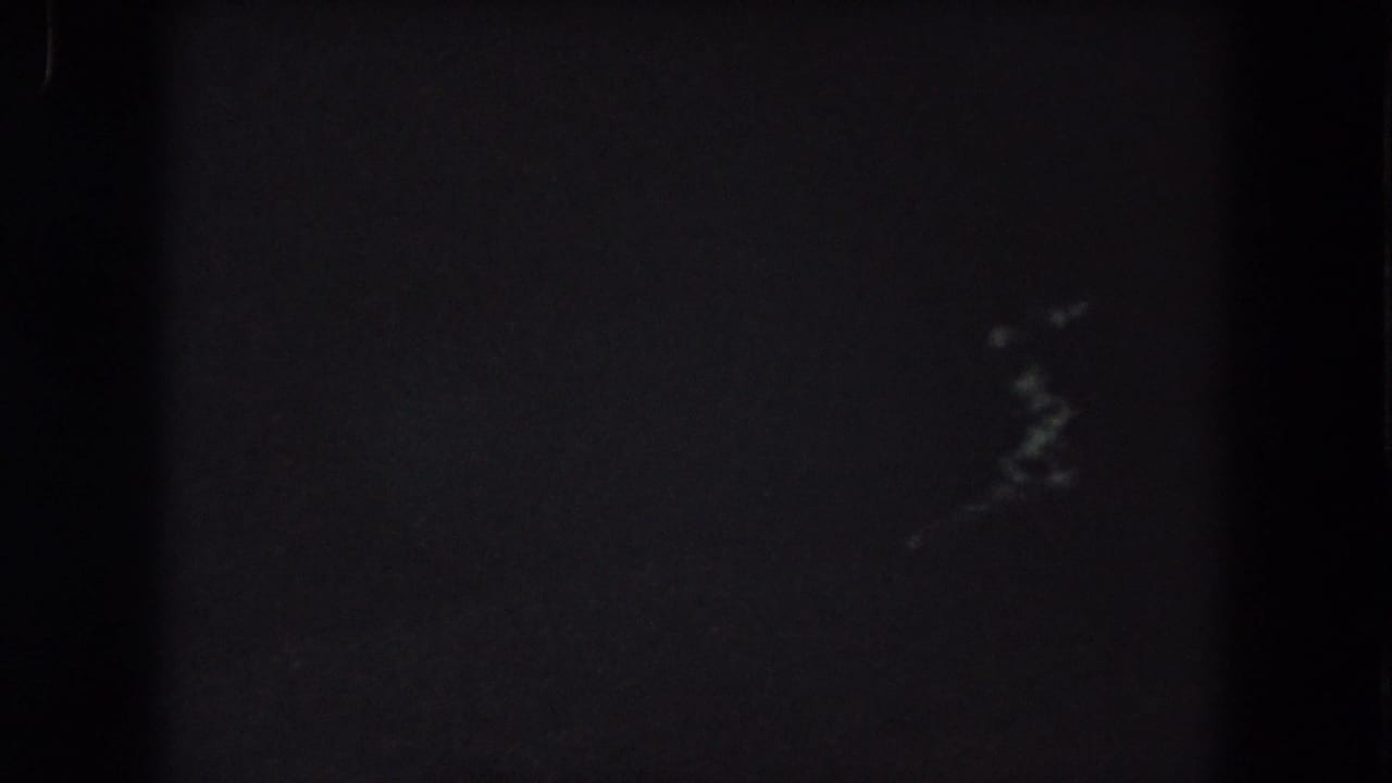 Dark low-exposure frame with small pale light streaks near the upper right.