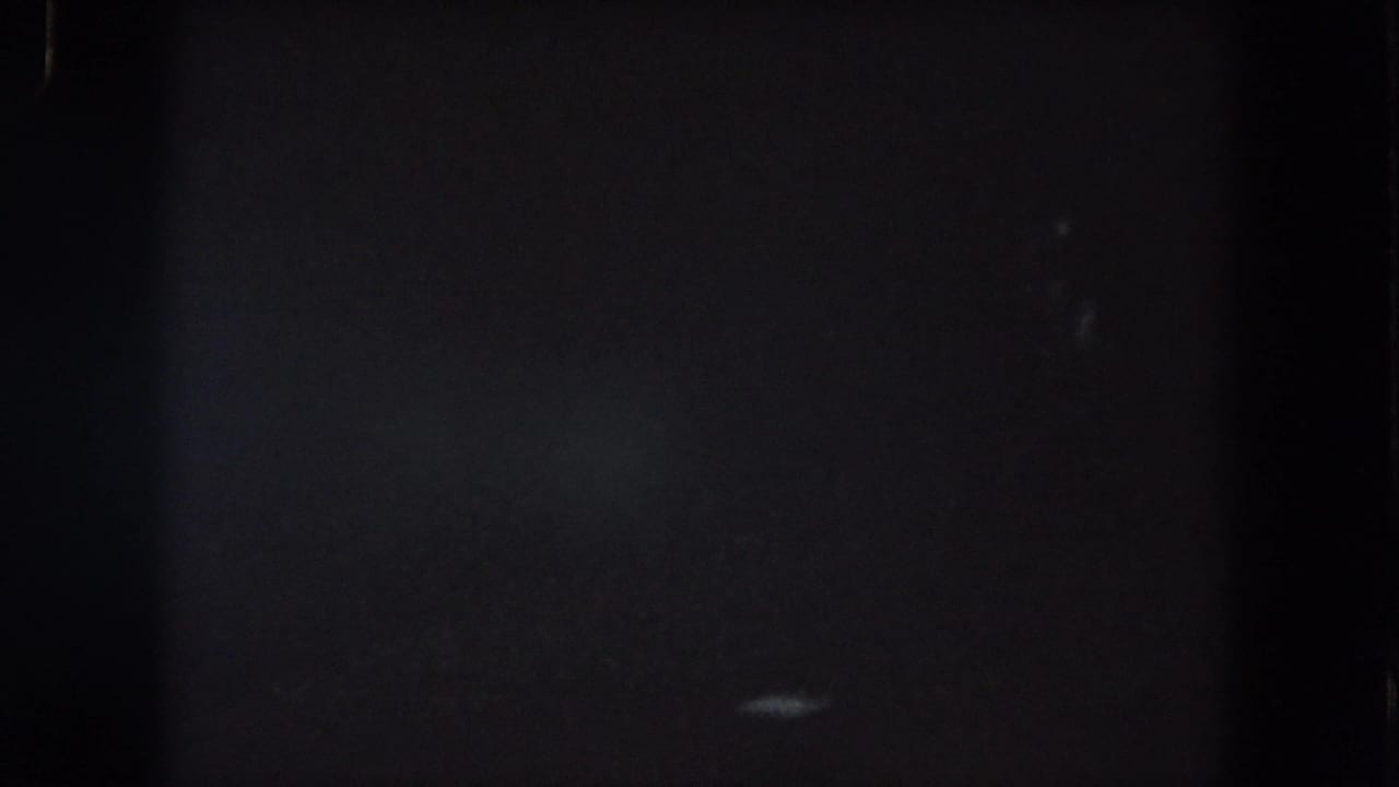 1962 Summit County 8mm frame with dim lower-right light smears, heavy grain, and little identifiable detail.