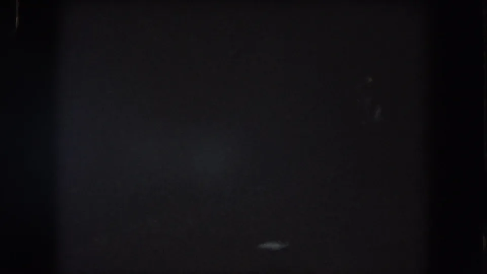 1962 Summit County 8mm frame with dim lower-right light smears, heavy grain, and little identifiable detail.