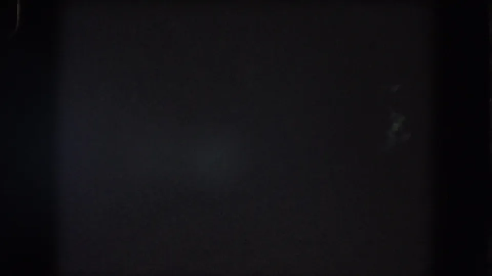 Dark 1962 8mm frame from Summit County, Colorado, with faint vertical marks, grain, and almost no visible landscape detail.