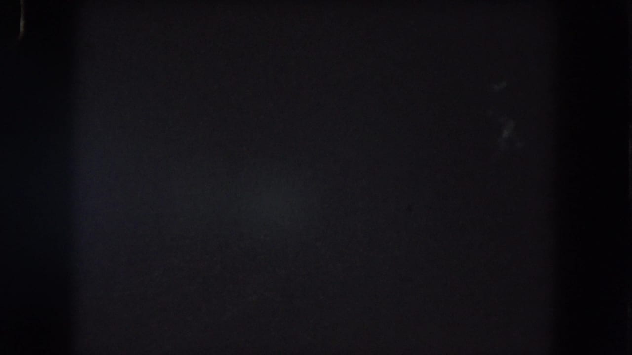 Underexposed Summit County 8mm night frame with a faint bluish area, visible grain, and dark vertical film divisions.