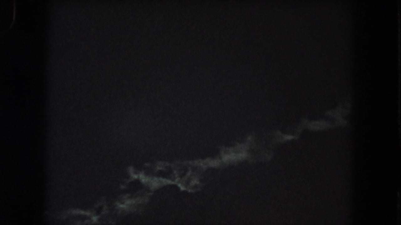 Grainy 1962 8mm night footage showing a faint greenish-white streak low in the frame against a nearly black background.