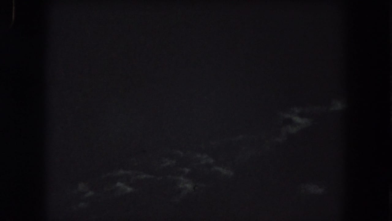 Very dark night sky with faint cloud streaks and heavy film grain.