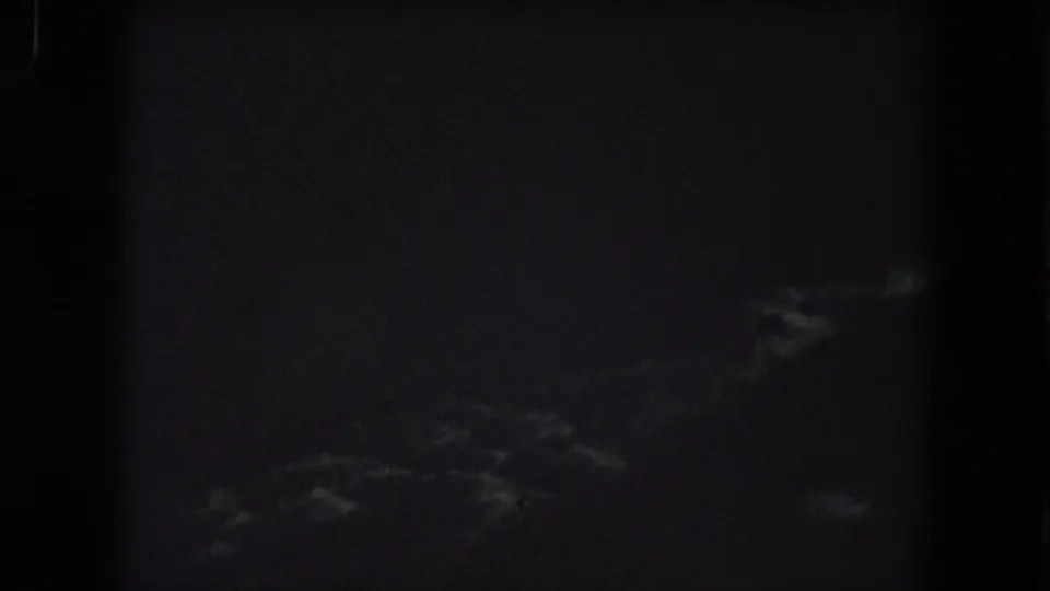 1962 Summit County, Colorado 8mm frame showing a nearly black night sky with dim wispy clouds and visible grain.