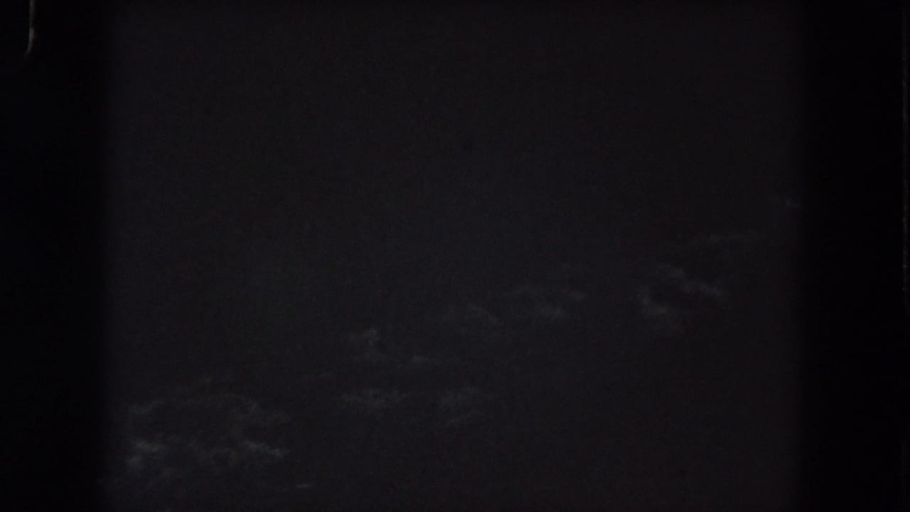 Underexposed 1962 Colorado home-movie frame with faint cloud texture across a dark night sky.