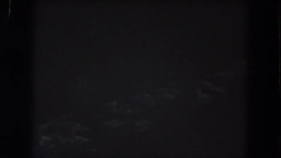 Underexposed 1962 Colorado home-movie frame with faint cloud texture across a dark night sky.