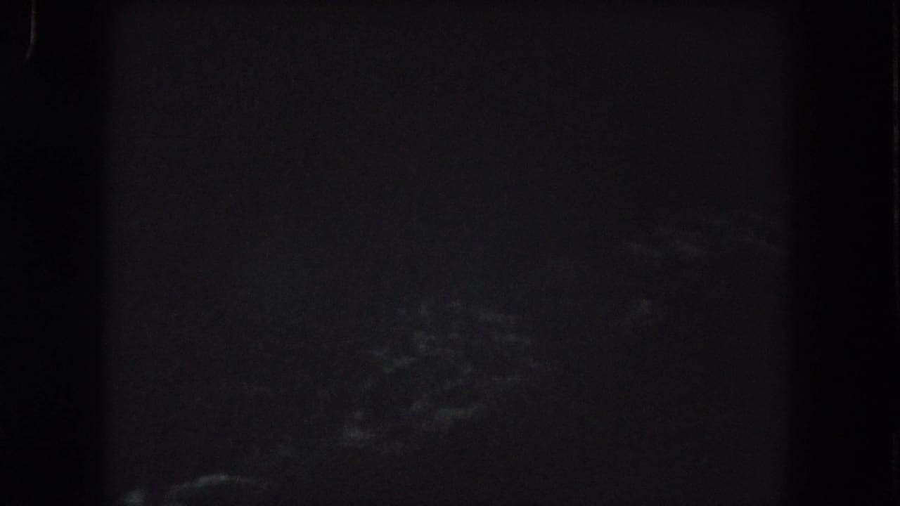 1962 Summit County 8mm frame showing faint cloud shapes low in a mostly black night sky.