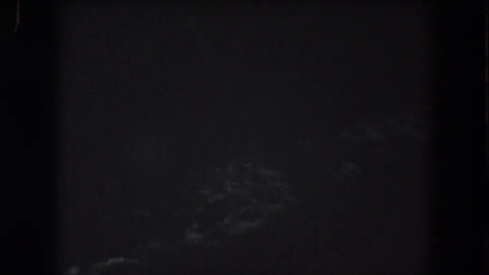 1962 Summit County 8mm frame showing faint cloud shapes low in a mostly black night sky.