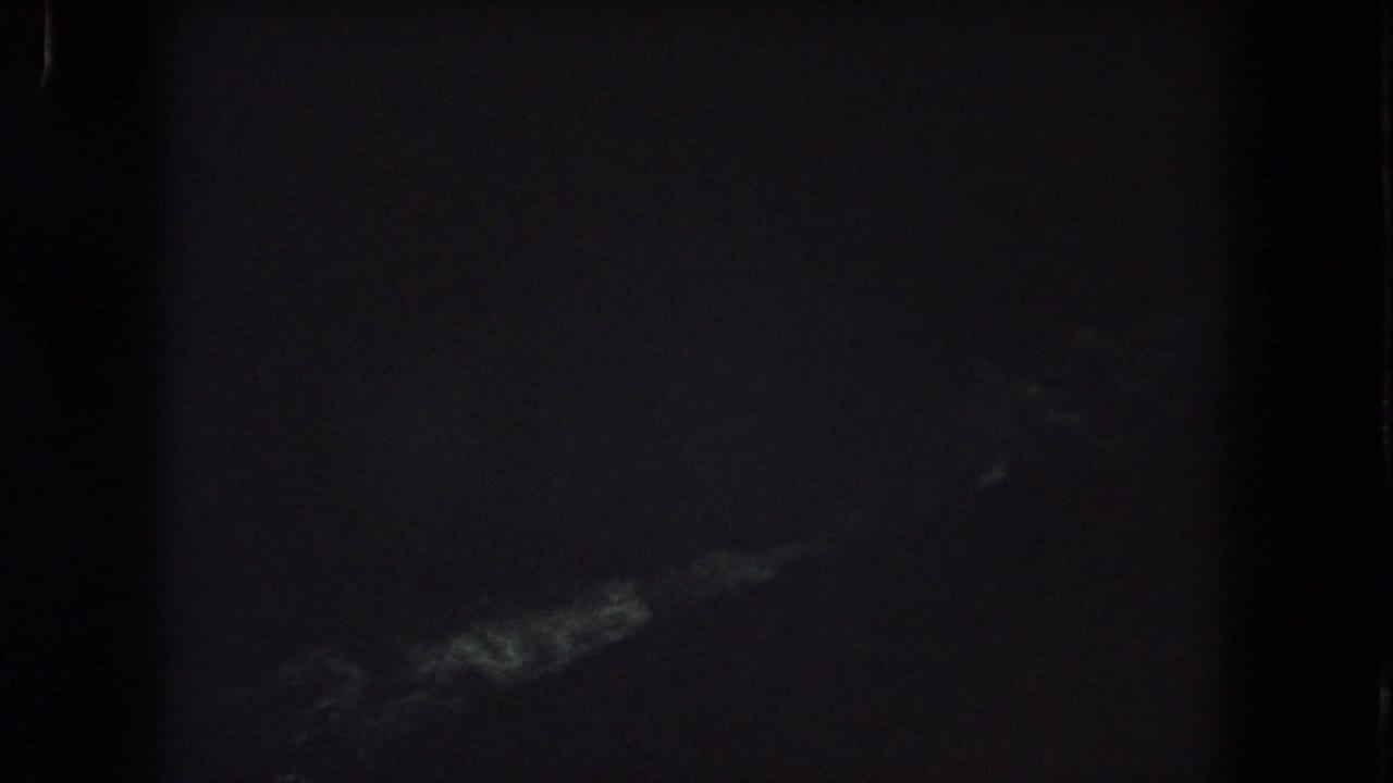 Grainy 1962 Colorado night-sky frame with a pale wispy cloud form visible near the bottom.