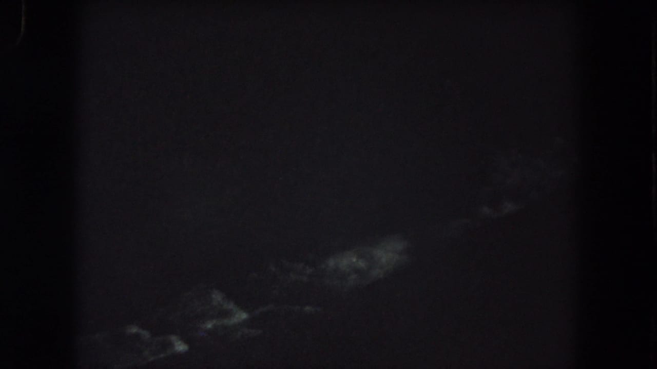 Underexposed 1962 8mm frame from Summit County showing indistinct pale forms in darkness, possibly trees or terrain.