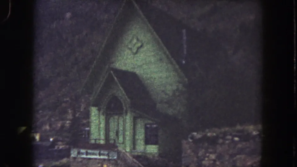 Small Summit County church exterior with Gothic-style opening, cross emblem, and muted 8mm color shift.