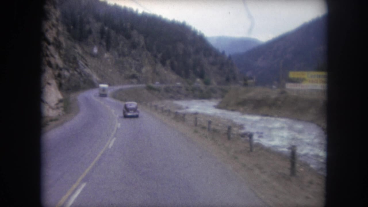 Winter Park, Colorado road footage shows a dark car and white vehicle on a curving highway beside a river and pine-covered slopes.