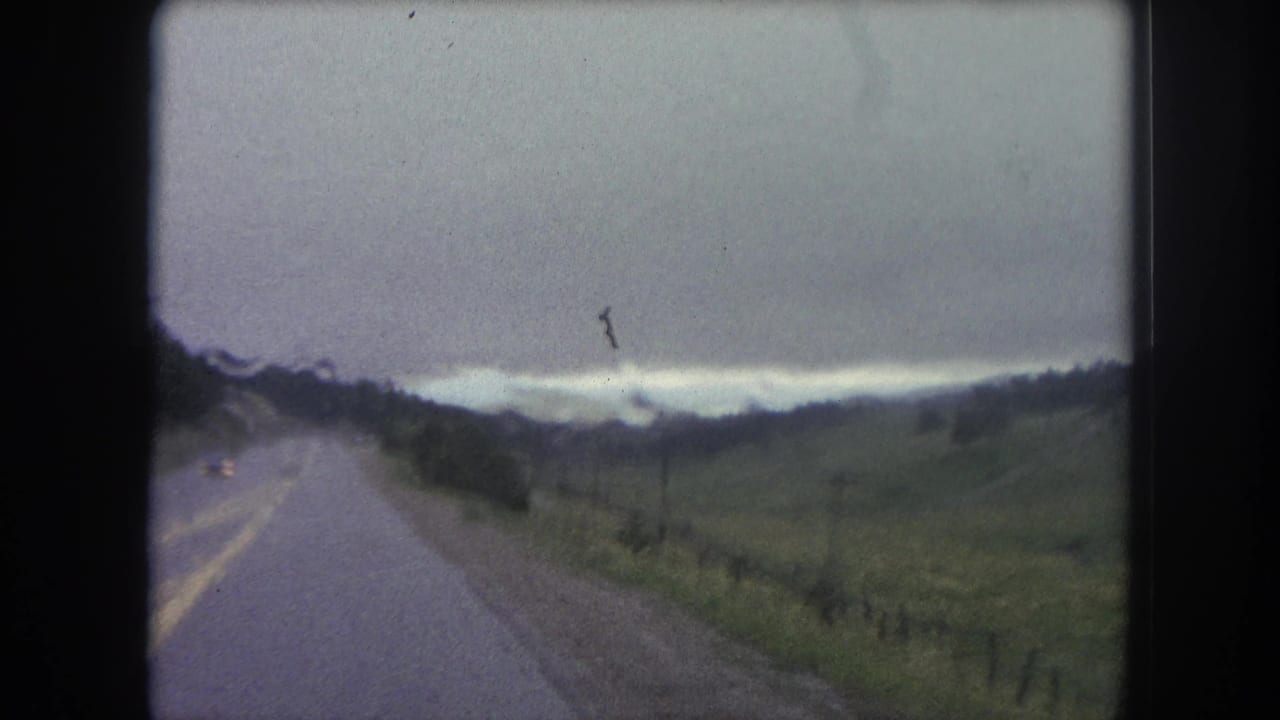 Forward-facing 8mm travel shot of a paved rural road through open Colorado hills near Winter Park in 1962.