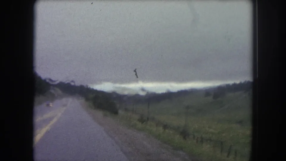 Forward-facing 8mm travel shot of a paved rural road through open Colorado hills near Winter Park in 1962.