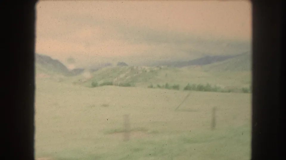 The clip shifts to an open Colorado field with low hills and a brighter sky, still rendered in soft 8mm color.