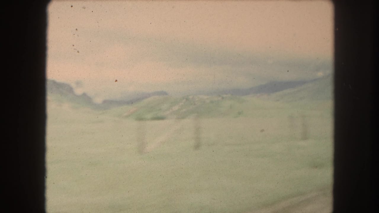 Distant hills and mountains with faint fence posts, framed by dark window edges.