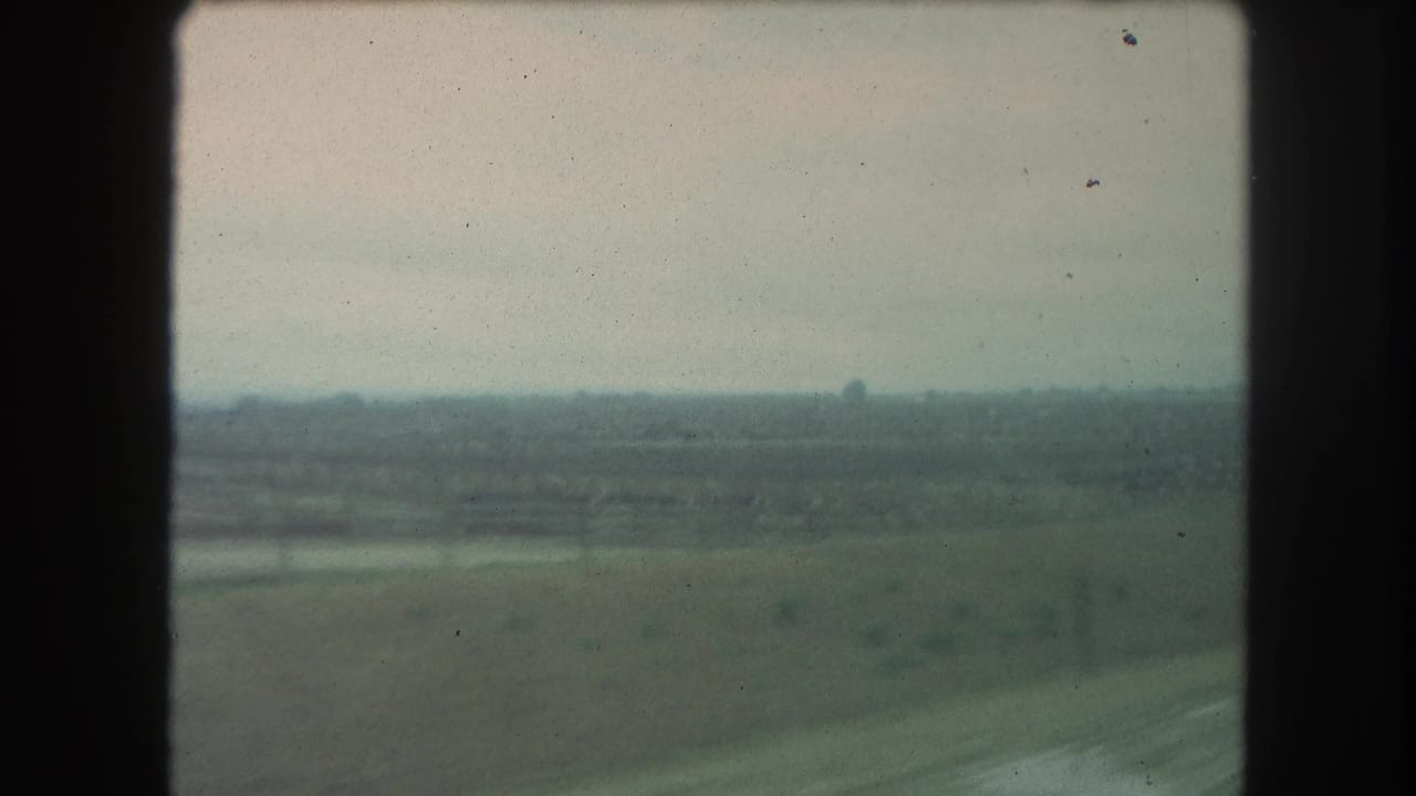 Wide rural landscape from a moving vehicle, with muted fields and soft horizon in 1962 8mm home-movie footage identified as Winter Park, Colorado.