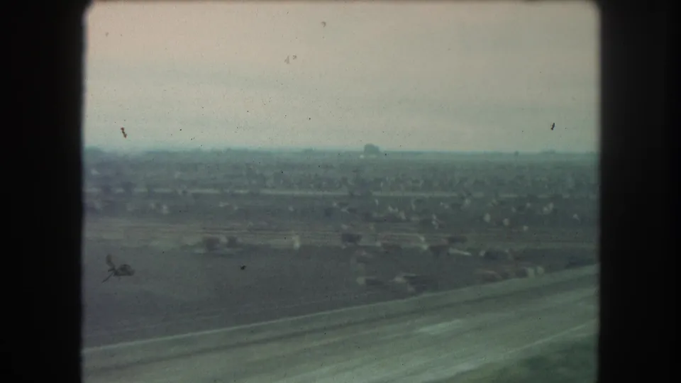 A 1962 train-window view shows open countryside, distant trees, and scattered structures near Winter Park, Colorado.