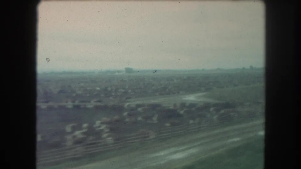 A passenger view from a 1962 train shows low fields, distant buildings, and soft haze near Winter Park, Colorado.